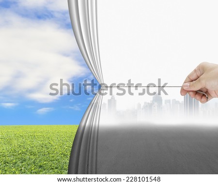 hand pulling gray cityscape curtain discovered natural sky meadow, environmental protection concept