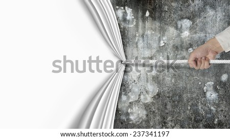 hand pulling blank curtain covered old dirty mottled concrete wall isolated on white background