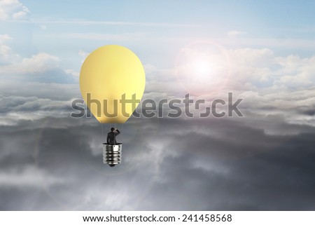 Businessman in glowing yellow lightbulb hot air balloon flying over natural sky daylight cloudscape background
