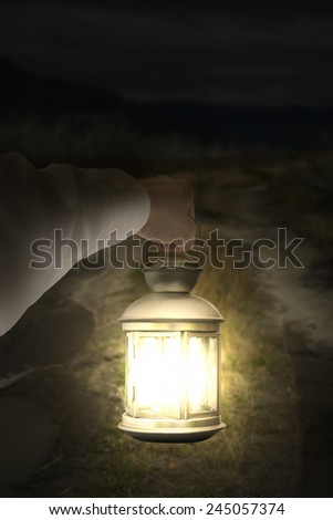 Left hand holding light illuminating dark road at night background