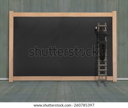 Businessman climbing ladder drawing on blank black board with dark green wood wall and floor background