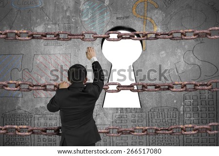 Businessman climbing on old iron chain for keyhole door with blank white view and business concept doodles wall background