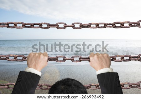 Businessman climbing on old iron chains to go out with natural sky sea background