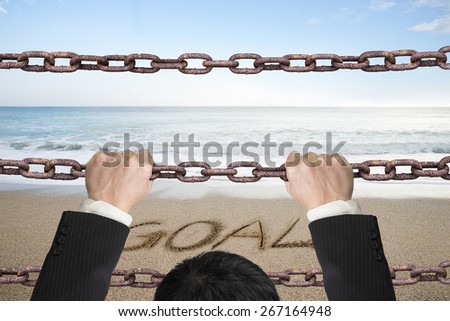 Businessman climbing on old iron chains to go out with goal word sand beach sea background
