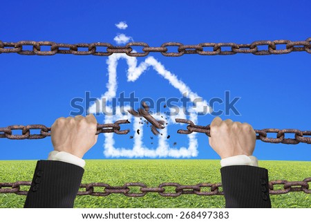 Rusty iron chains broken off by hands with house shape white clouds on sky grass background