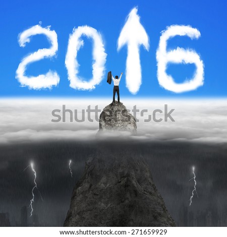 Businessman cheering on mountain peak for white 2016 year arrow up sign shape clouds in the sky with opposite weather conditions background, blue sky cloudscape, dark lightning raining cityscape
