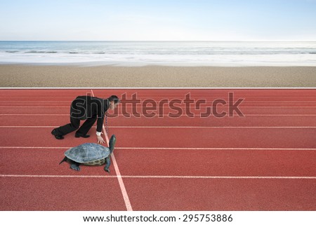 Businessman and turtle are ready to race on running track, with natural sea beach background. Turtle race competing metaphor concept.
