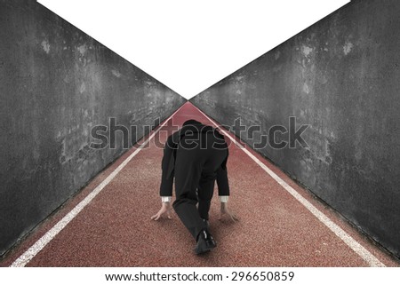 Businessman ready to race on running track, with concrete wall and isolated on white background.