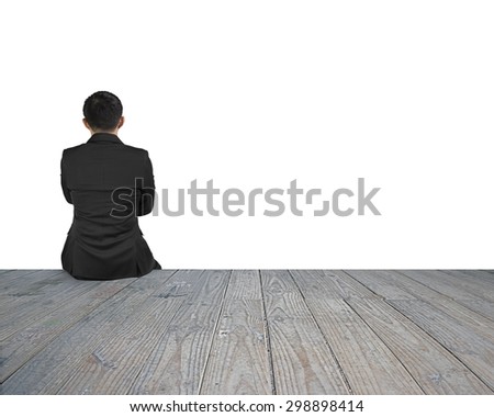 Rear view of black suit man sitting on wooden floor with white background.