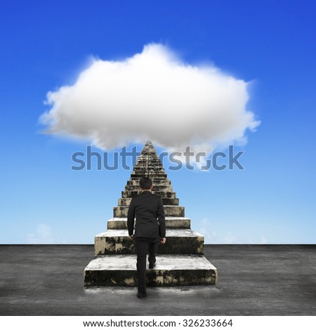 Businessman steps up old concrete stairs toward white cloud in blue sky background.