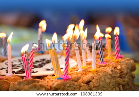 Colorful candles on  birthday cake above dark background