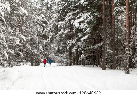 Two people walking in the winter snowy forest