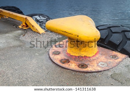 Yellow mooring bollard on concrete pier
