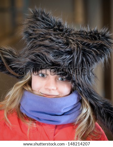 Little blond girl in fun artificial fur hat. Closeup portrait