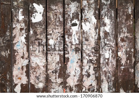 Old wooden fence background texture with scraps of paper ads