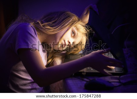 Little blond girl open laptop and looks inside