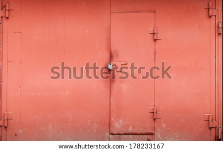 Red metal garage wall with locked gate. Background texture