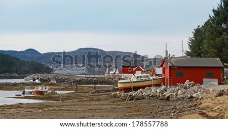 Norwegian red wooden houses and small fishing boats on the sea coast
