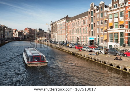 AMSTERDAM, NETHERLANDS - MARCH 19, 2014: Sightseeing pleasure boat goes through the canal in historical center of Amsterdam