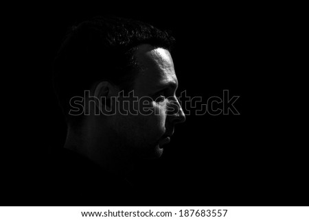 Monochrome profile portrait of young Caucasian man on black background