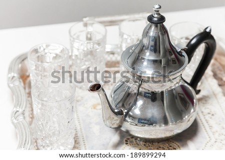 Moroccan tea theme. Shining metal teapot with glasses