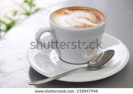 White cup of cappuccino stands on the table, selective focus