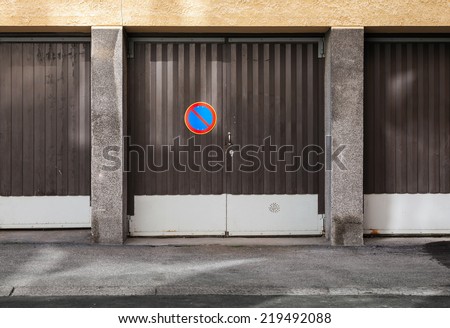 Brown metal garage gates with no parking road sign