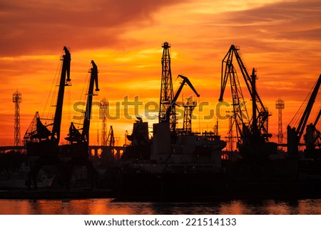 Silhouettes of cranes and cargo ships in port of Varna at sunset