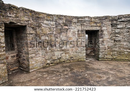 Round ruined interior with empty windows of old stone fort tower. Koporye Fortress, Russia