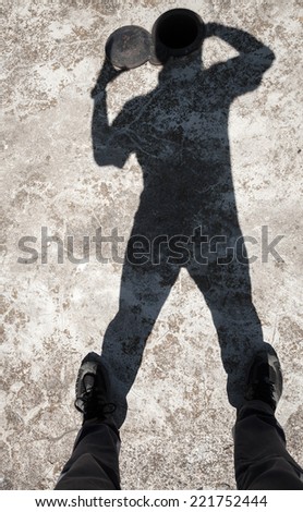 Shadow of a man opens small hatch in head on old concrete floor