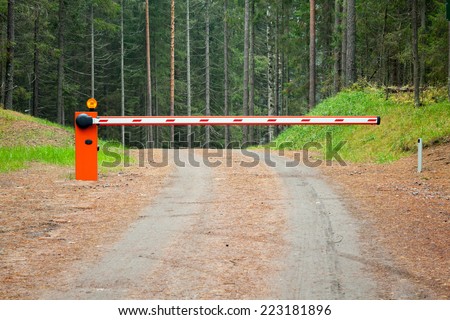 Rural road in the forest with closed red white barrier
