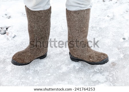 Male feet with traditional Russian felt boots on winter snowy road