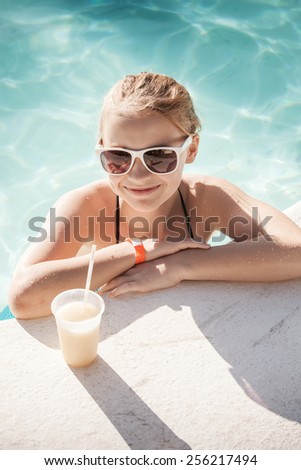 Little blond girl with cocktail in swimming pool, vintage toned photo filter effect