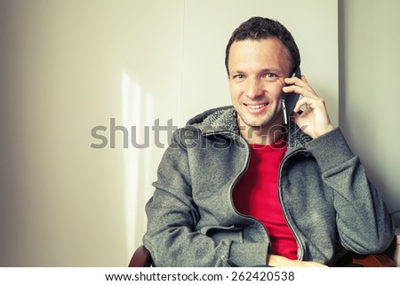 Portrait of sitting young Caucasian man talking on mobile phone. Vintage toned photo with old style filter effect