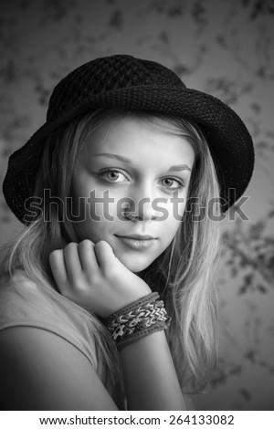 Monochrome portrait of beautiful blond teenage girl in black hat and rubber loom bracelets