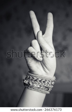 Child hand showing victory sign with rubber rainbow loom bracelets on wrist, trendy teenagers fashion accessories. Monochrome vintage retro tonal photo filter correction