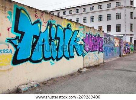 Saint-Petersburg, Russia - April 7, 2015: Colorful chaotic graffiti text patterns on old concrete fence