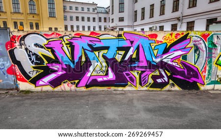Saint-Petersburg, Russia - April 7, 2015: Colorful chaotic graffiti text patterns over old concrete fence