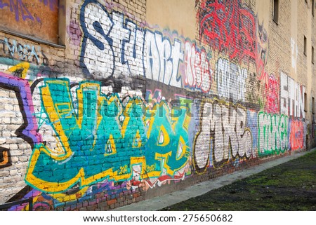 Saint-Petersburg, Russia - May 6, 2015: Abandoned urban courtyard with colorful abstract graffiti text over old damaged wall. Vasilievsky island, Central part of St. Petersburg