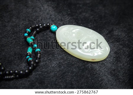 Hangzhou, China - December 2, 2014: Traditional Chinese stone amulet made of jade with dragon art carving lays on black counter in gemstones shop. Selective focus and shallow DOF
