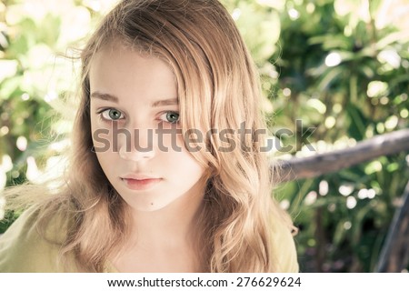 Closeup outdoor portrait of beautiful blond Caucasian teenage girl in a park with natural light, vintage toned photo filter effect, instagram style