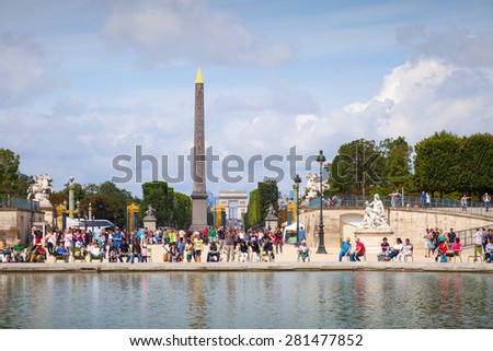 Paris, France - August 09, 2014: Pond in Jardin des Tuileries with walking tourists, view on Avenue des Champs-Elysees and Place de la Concorde