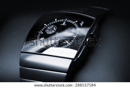 Luxury mens chronograph watch made of black high-tech ceramics lays on leather backdrop. Closeup studio photo with selective focus