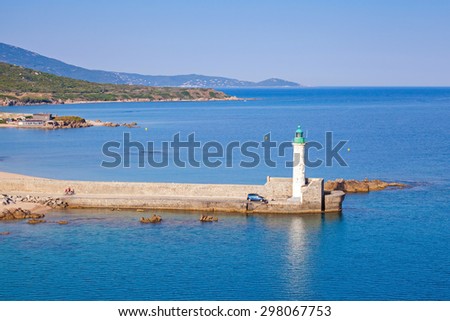 White lighthouse tower on stone pier. Entrance to Propriano port, Corsica, France