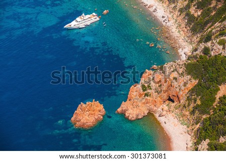 Luxury white pleasure yacht anchored near rocky beach of Corsica island, birds eye view