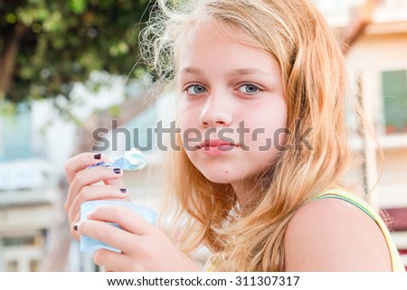 Blond Caucasian teenage girl with frozen yogurt, closeup outdoor portrait with natural light