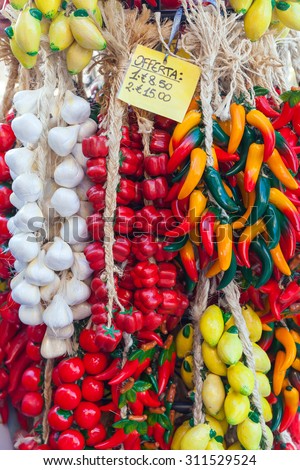 Decorative vegetables and fruits with price label hang on the counter of Italian souvenir shop