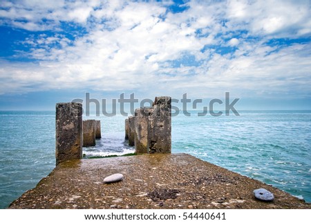 Black Sea coast: old wet pier with columns with perfect sky and sea on background. Russia, Sochi, Adler.