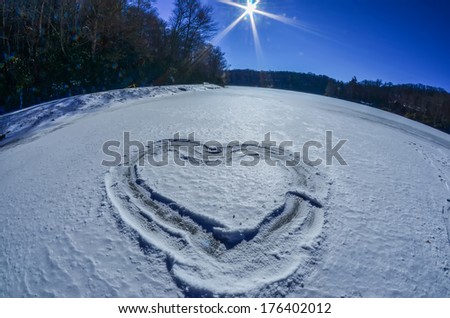 heart outlined on snow on topw of frozen lake