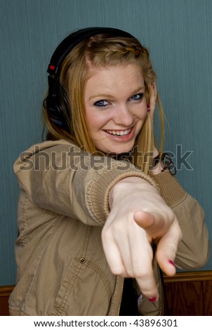 Young Woman listening to music and pointing at camera